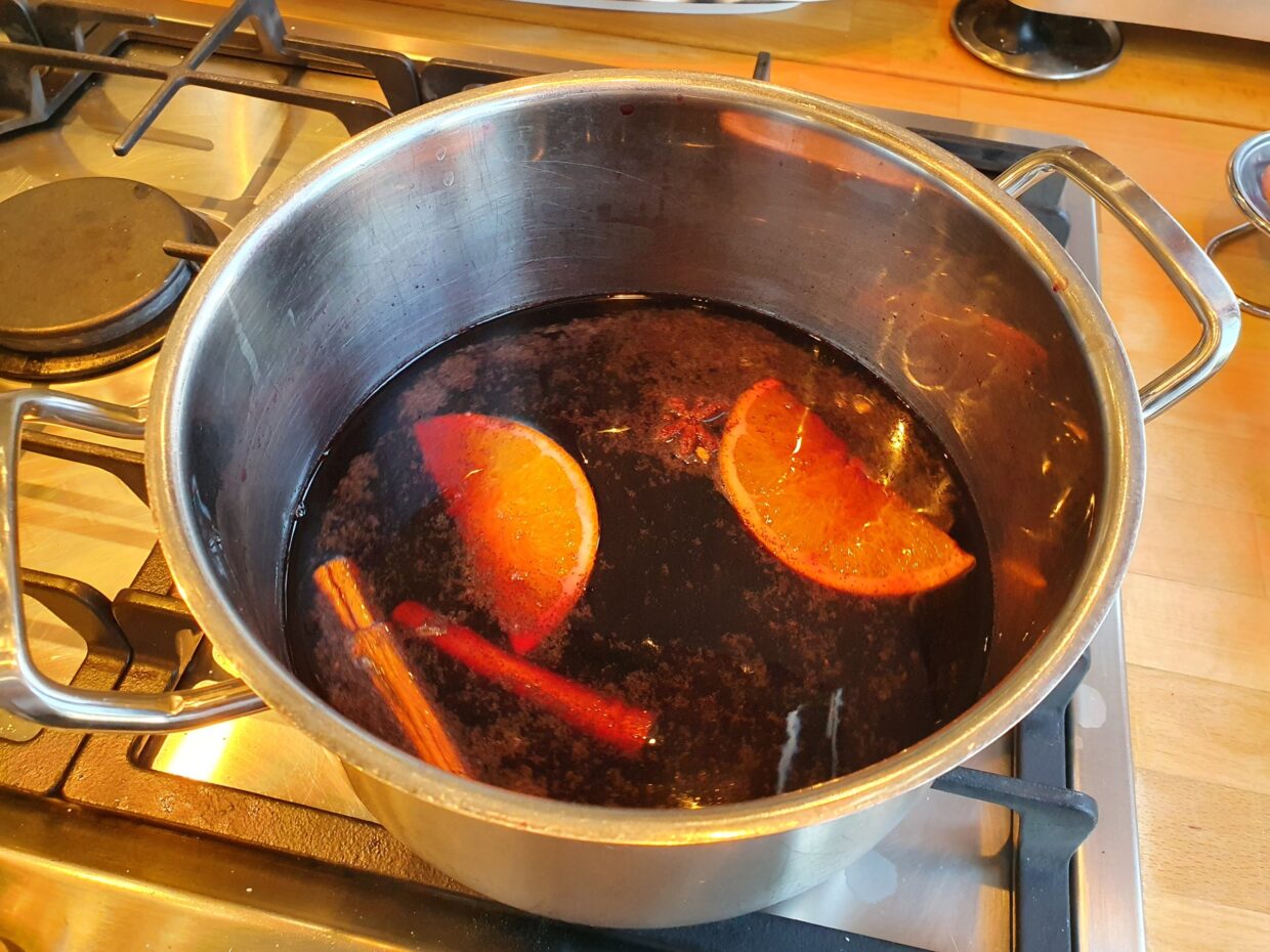 Glühwein wird im Topf auf dem Herd zubereitet.